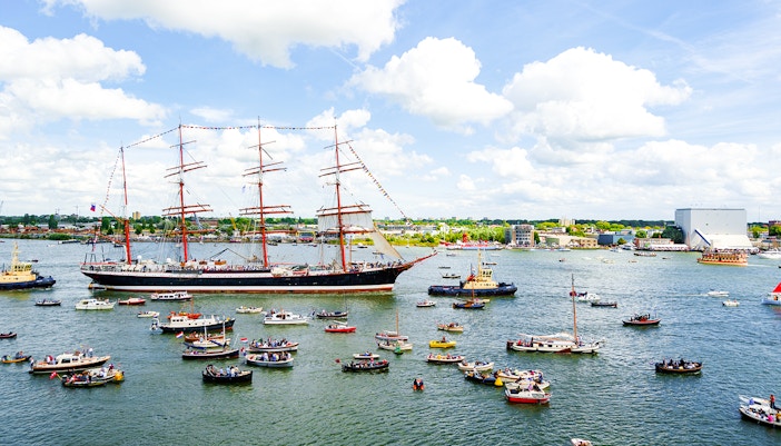 Tall ships and boats on the IJ River during Sail Amsterdam event.