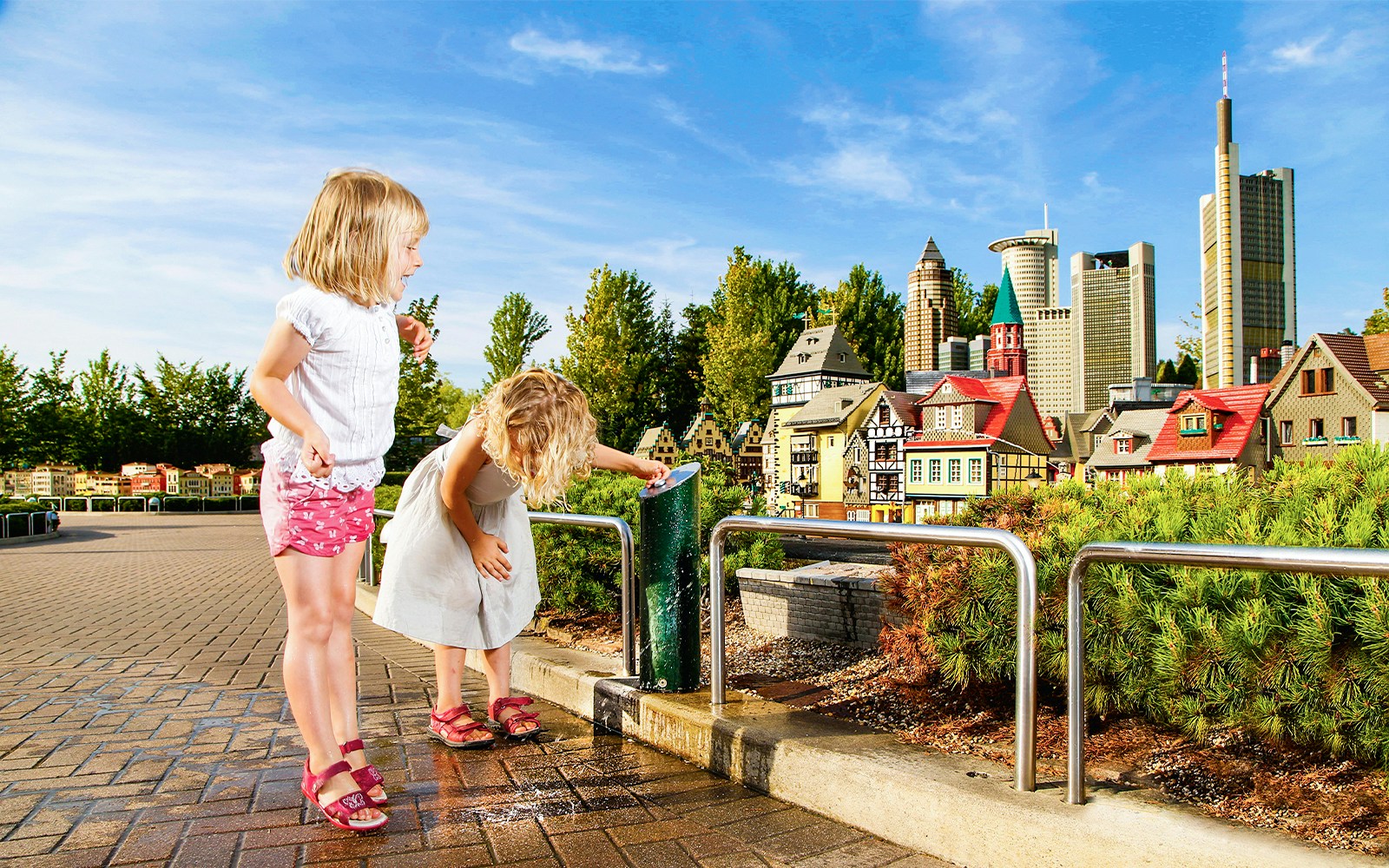 Children interacting with water feature at MINILAND in LegoLand Resort Germany, with miniature cityscape in background.