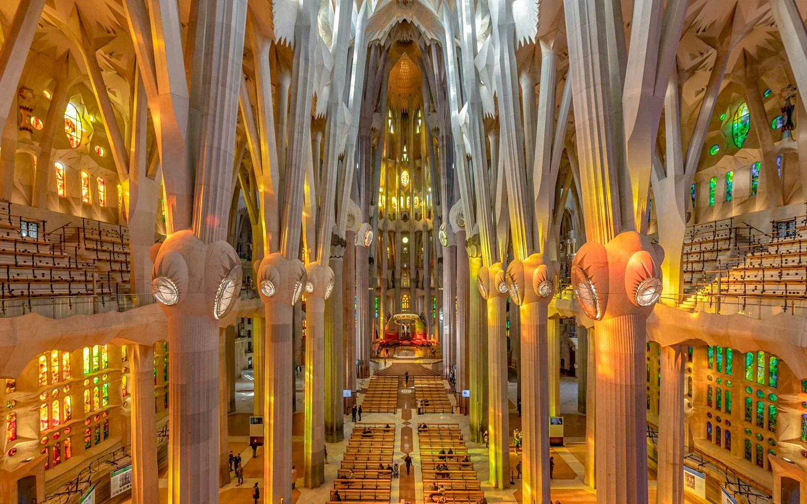 Sagrada Familia interior with towering columns and colorful stained glass windows.