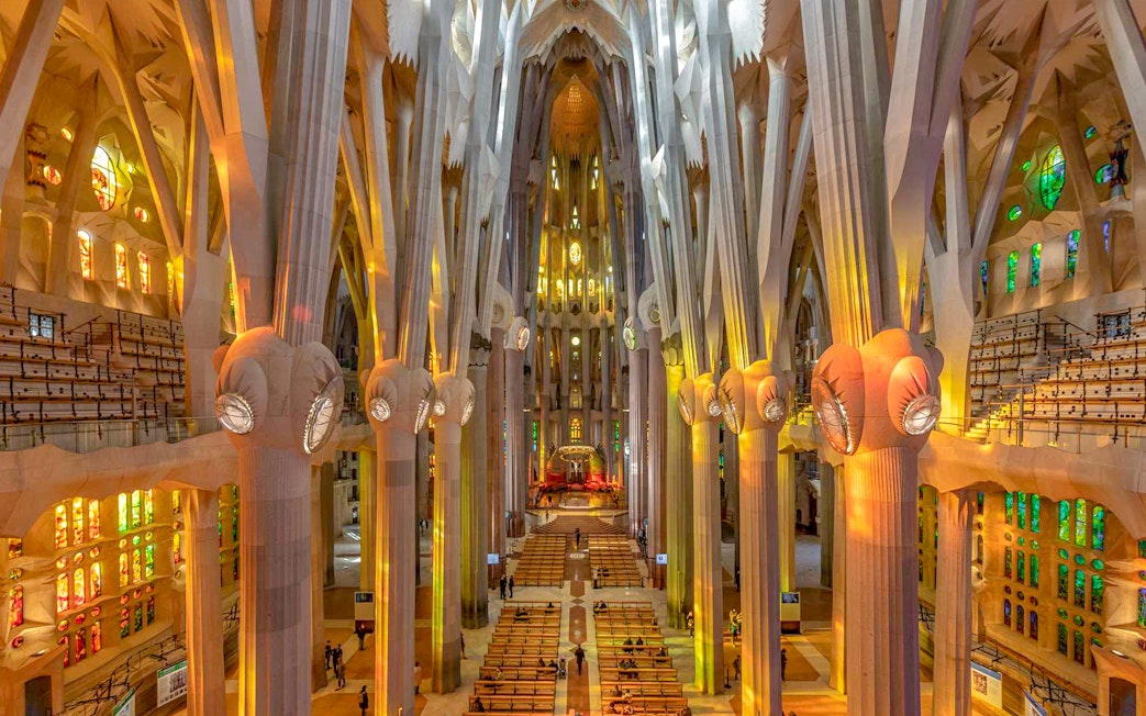 Sagrada Familia interior with towering columns and colorful stained glass windows.