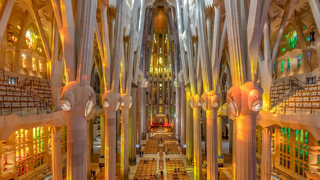 Sagrada Familia interior with towering columns and colorful stained glass windows.