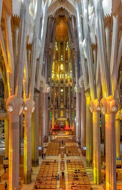 Sagrada Familia interior with towering columns and colorful stained glass windows.