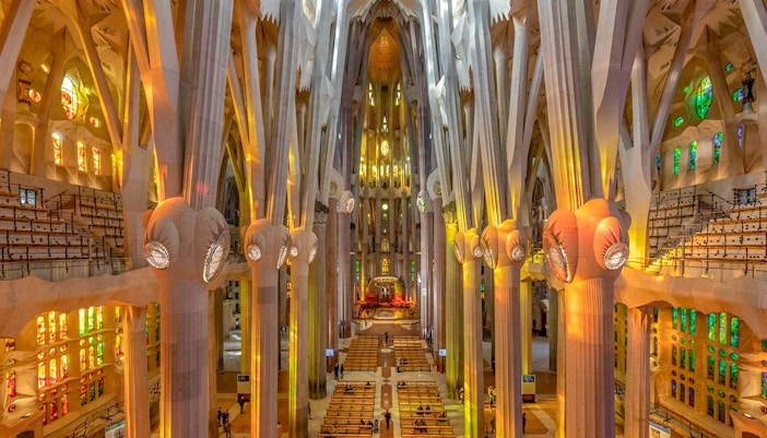 Sagrada Familia interior with towering columns and colorful stained glass windows.