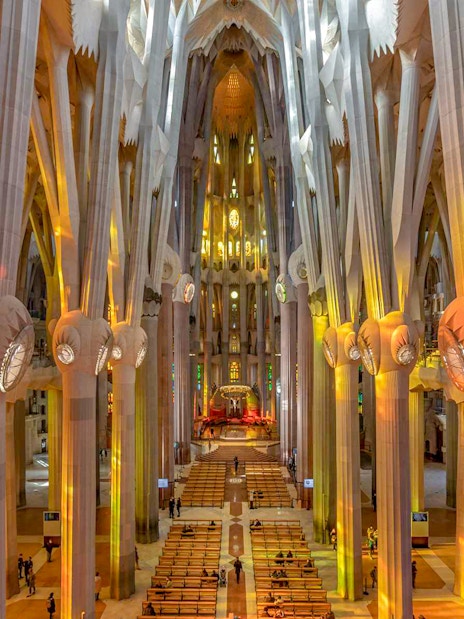 Sagrada Familia interior with towering columns and colorful stained glass windows.