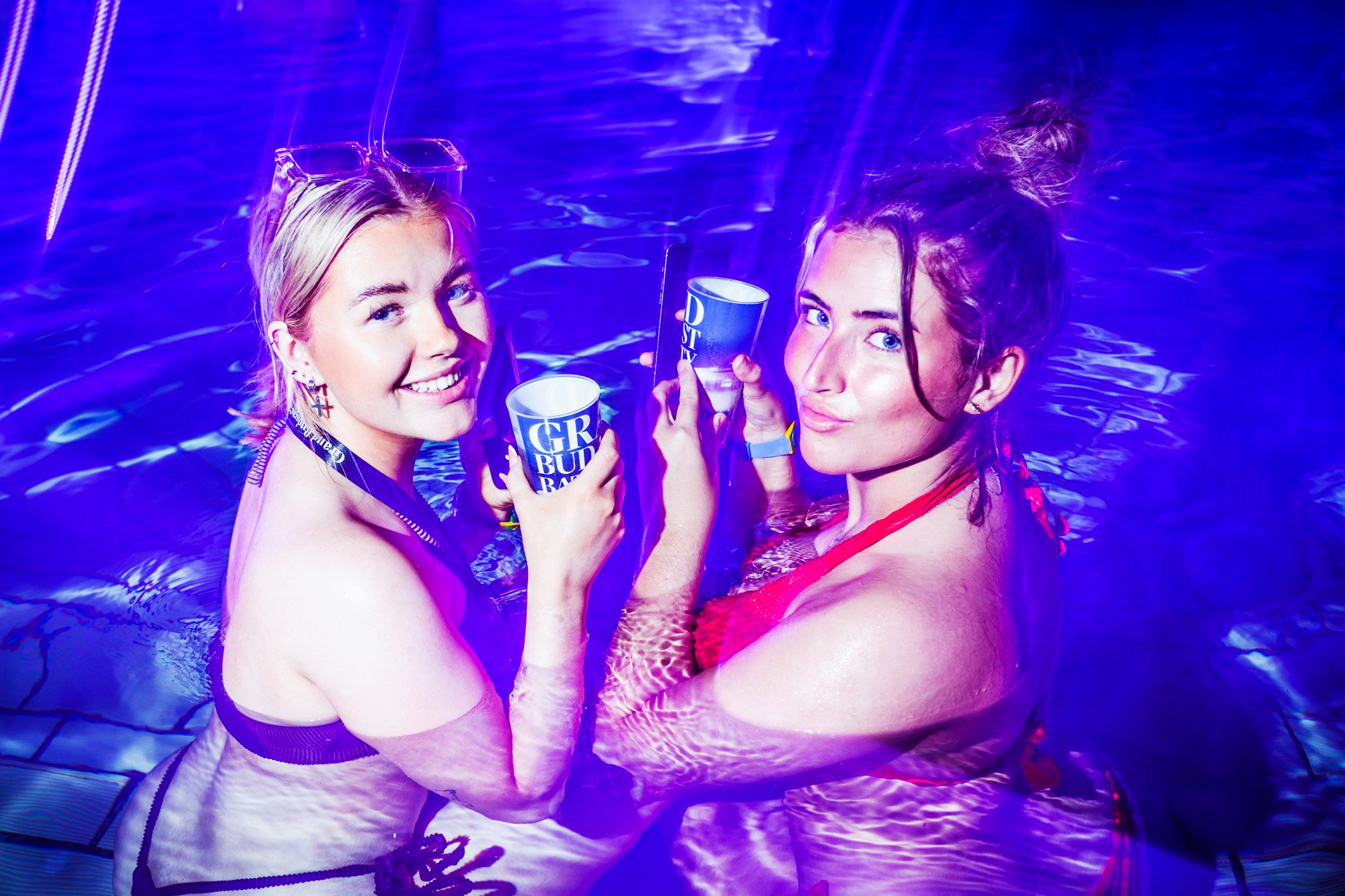 Nighttime pool party at Széchenyi Thermal Bath, Budapest, with vibrant lights and lively crowd.