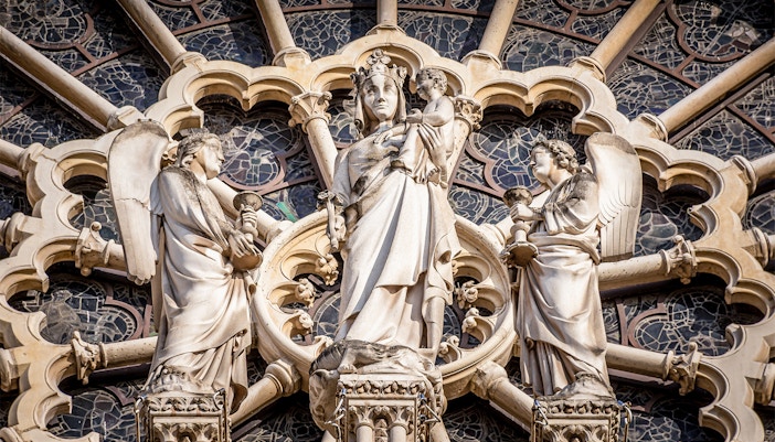 Notre Dame Cathedral facade with Virgin Mary statue, Paris, France.