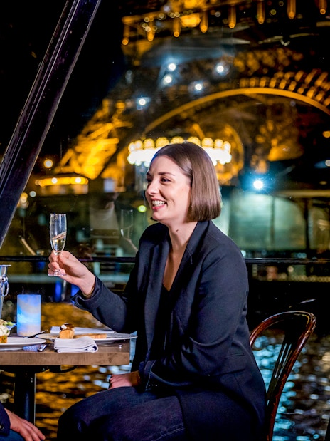 Couple enjoying dinner on Seine River cruise with Eiffel Tower view.
