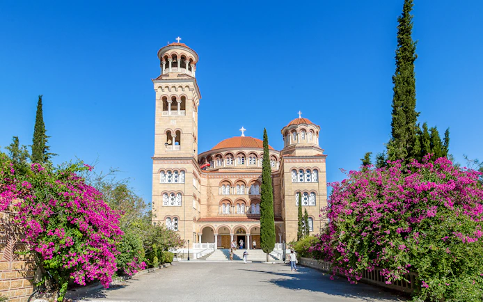 Saint Nektarios church with bell tower and flowers, Aegina island, Greece.