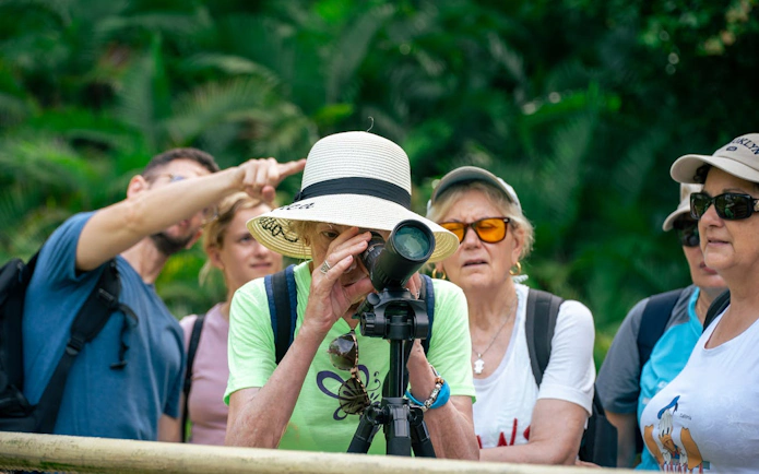 Tourists observing wildlife through a telescope in Manuel Antonio National Park.