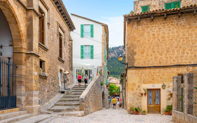 Valldemossa street with stone buildings and tourists exploring, part of the Valldemossa and Soller Tour.