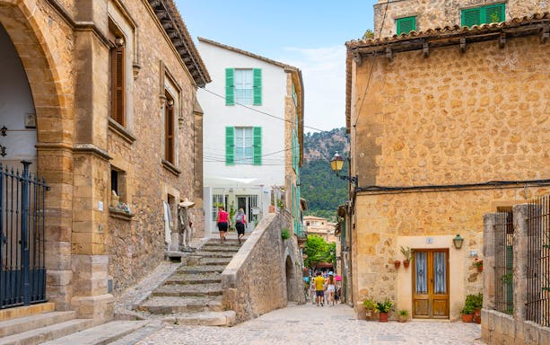Valldemossa street with stone buildings and tourists exploring, part of the Valldemossa and Soller Tour.