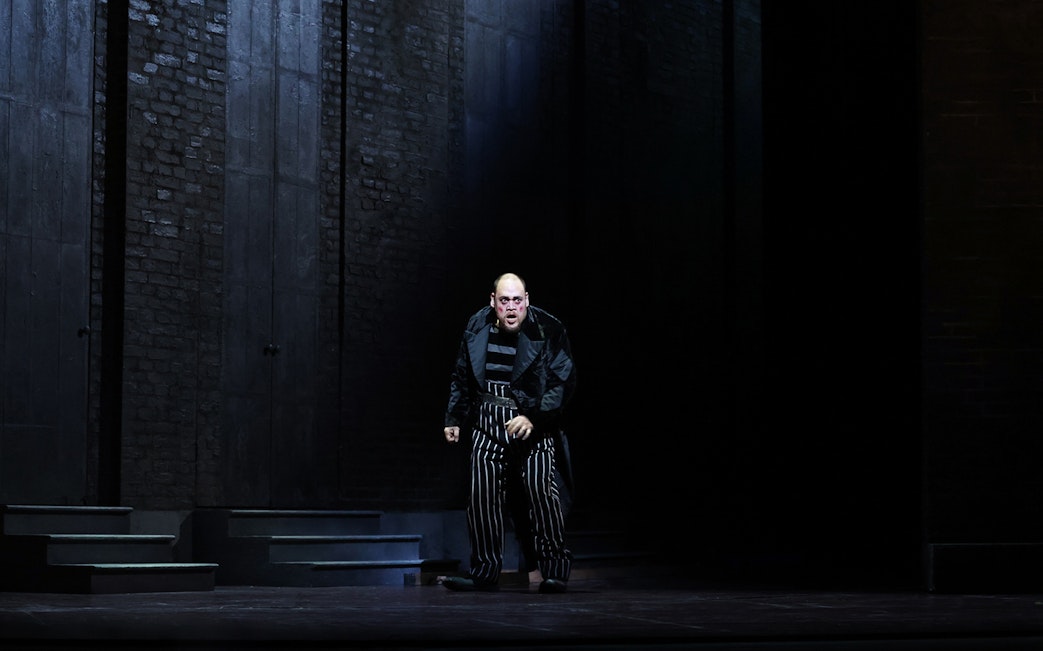 Performer in striped costume on stage during Rigoletto opera.