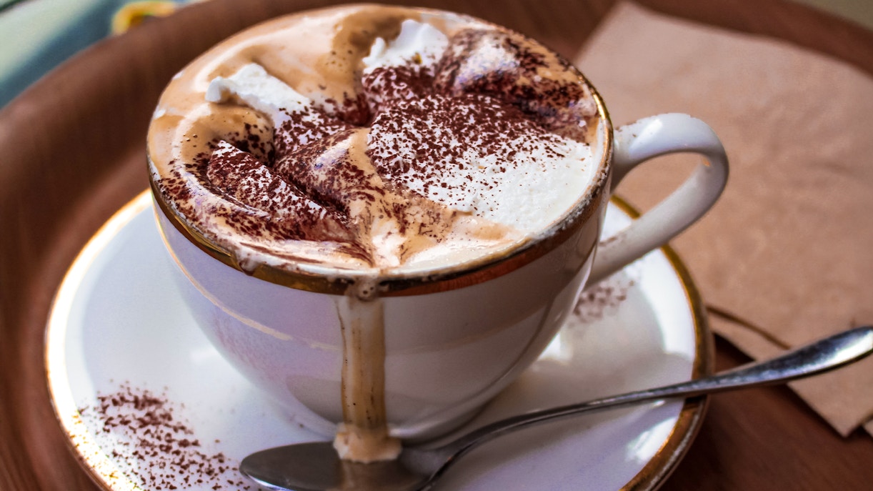 Cup of mocha latte with whipped cream and cocoa powder.