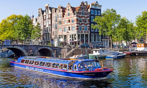 Amsterdam canal tour boat cruising under a historic bridge on the Blue Boat Cruise.