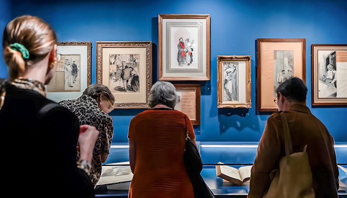 Visitors viewing framed art and documents at the Montmartre Museum exhibit.
