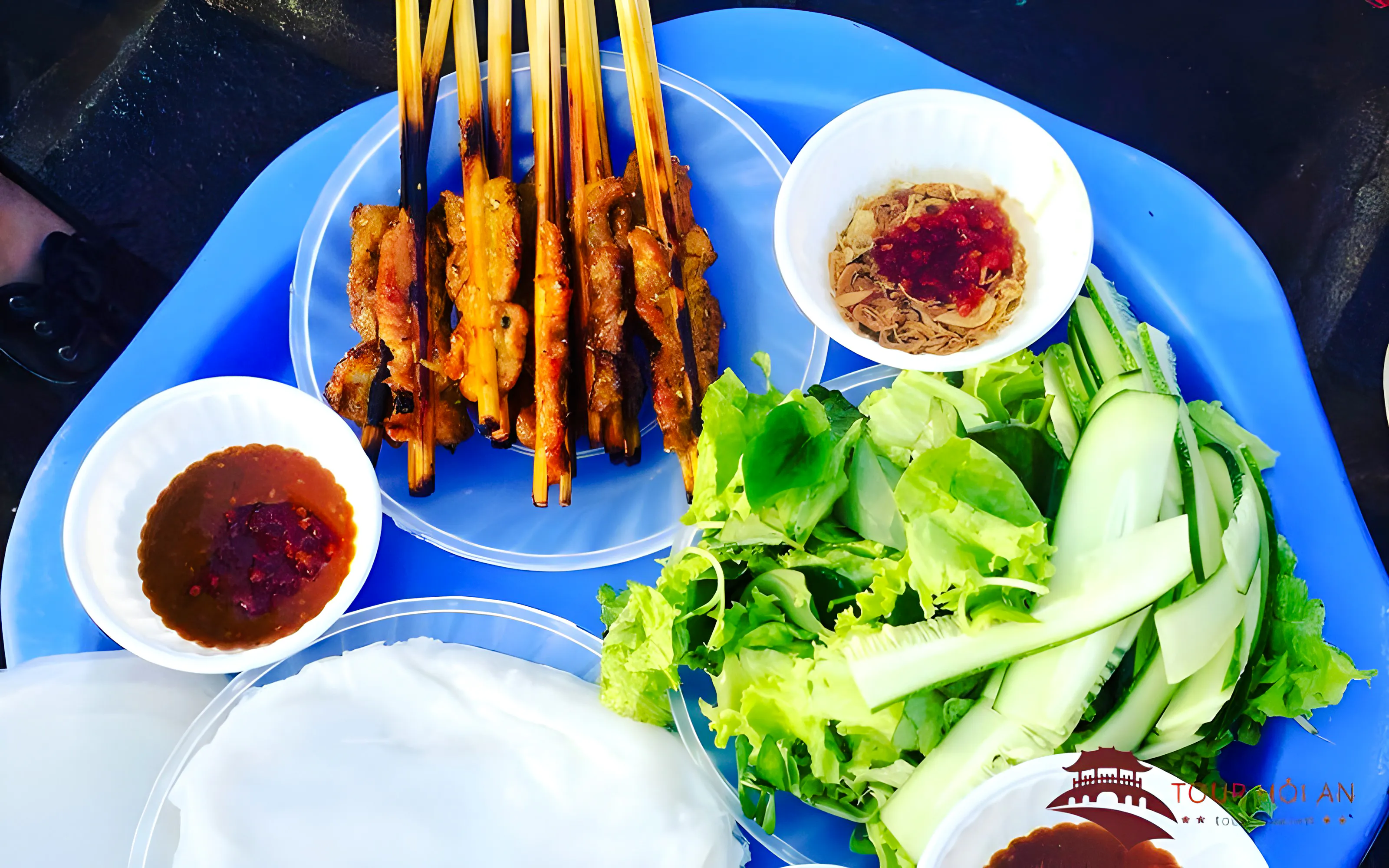 Grilled skewers with fresh vegetables and dipping sauces in Da Nang, Vietnam.