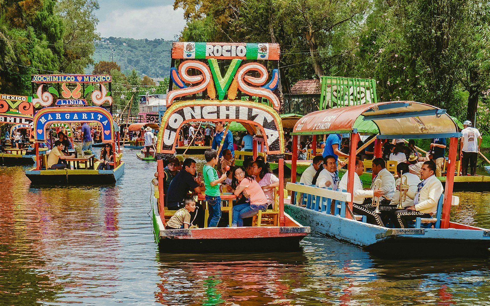 Trajinera boats with people enjoying a party in Xochimilco, Mexico.