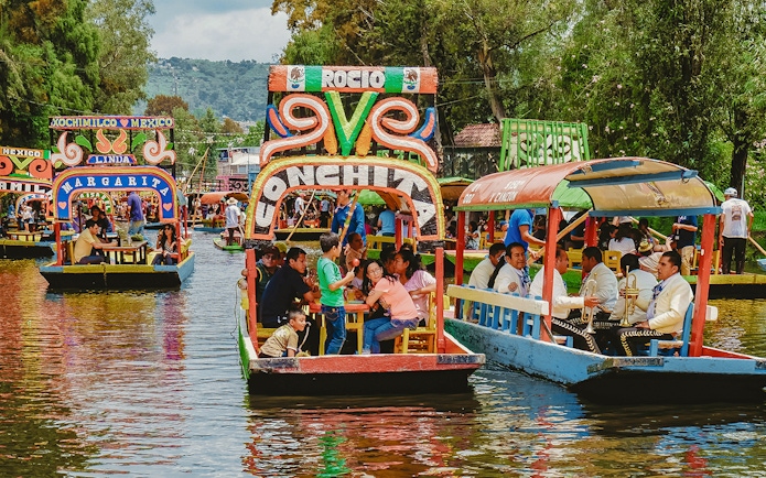Trajinera boats with people enjoying a party in Xochimilco, Mexico.