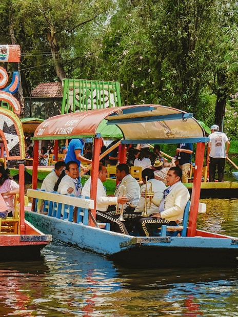 Trajinera boats with people enjoying a party in Xochimilco, Mexico.