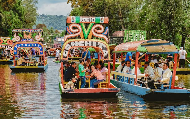 Trajinera boats with people enjoying a party in Xochimilco, Mexico.