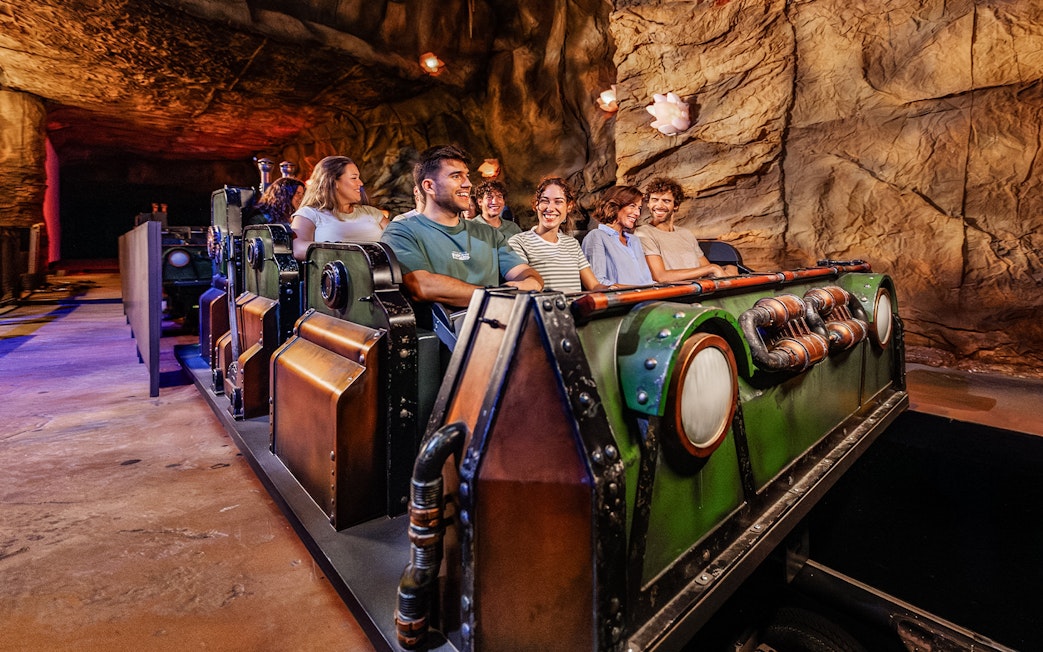 Visitors enjoying the Uncharted ride at PortAventura in a cave-themed setting.