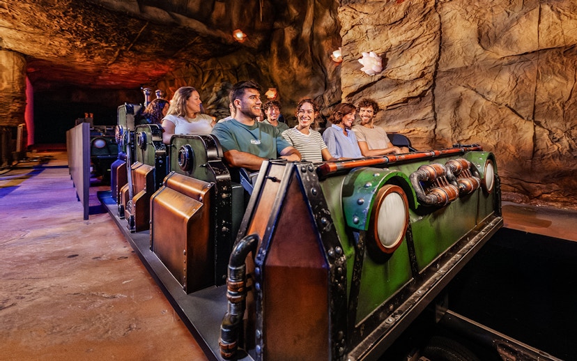 Visitors enjoying the Uncharted ride at PortAventura in a cave-themed setting.