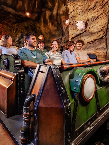 Visitors enjoying the Uncharted ride at PortAventura in a cave-themed setting.