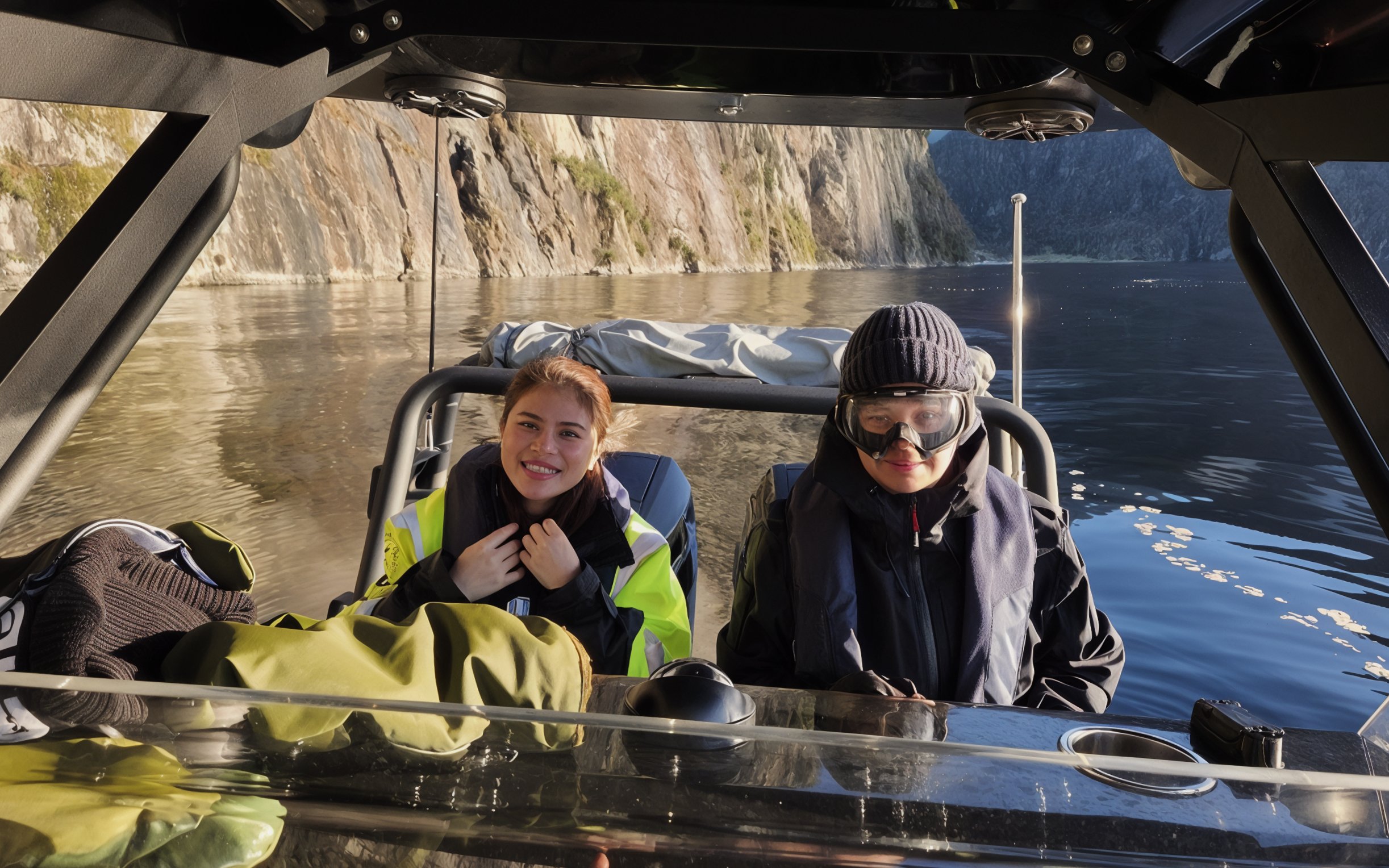 Passengers in safety suits enjoying a boat ride on a scenic fjord.