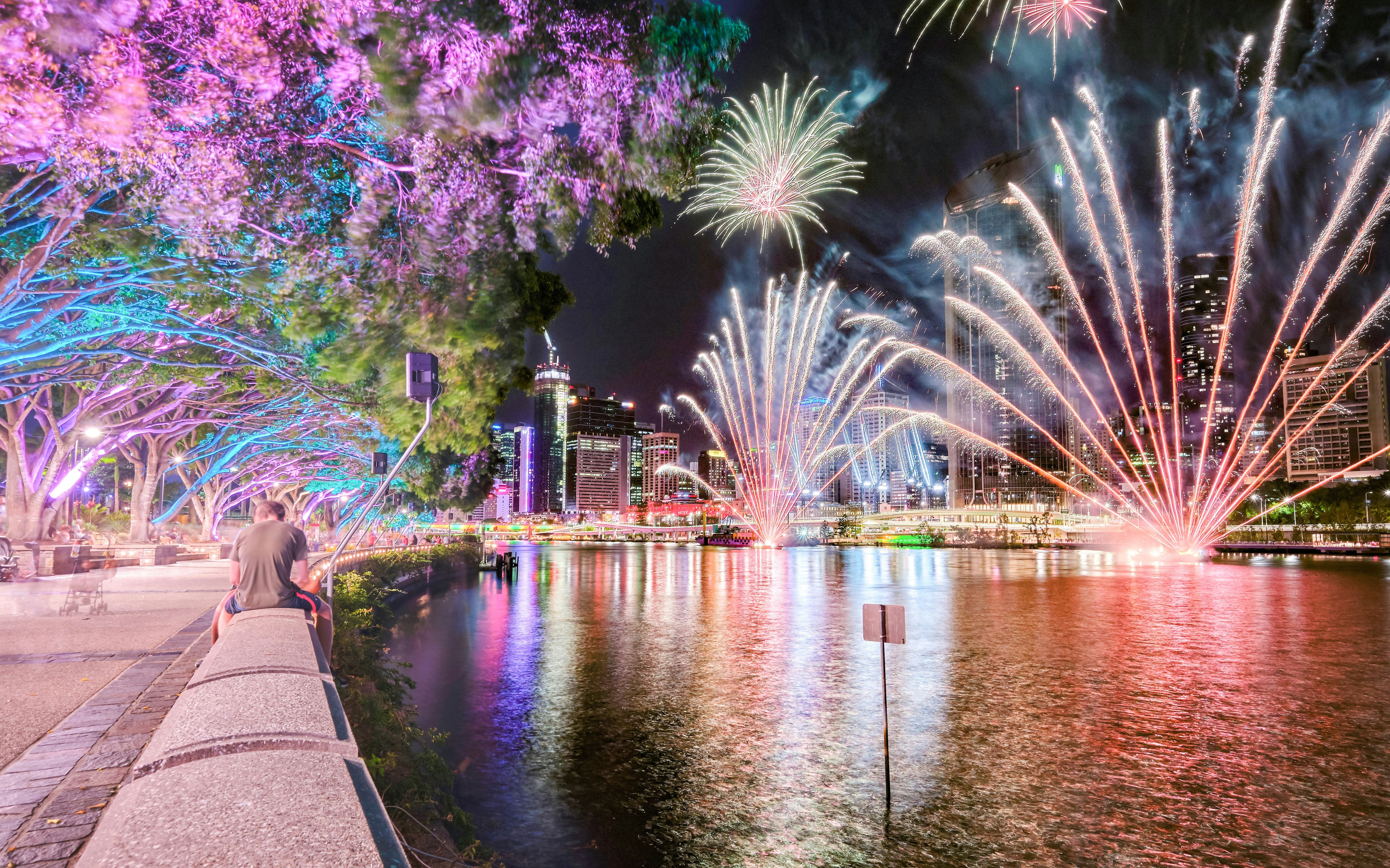 Brisbane River fireworks with colorful trees and people at Southbank during Christmas.