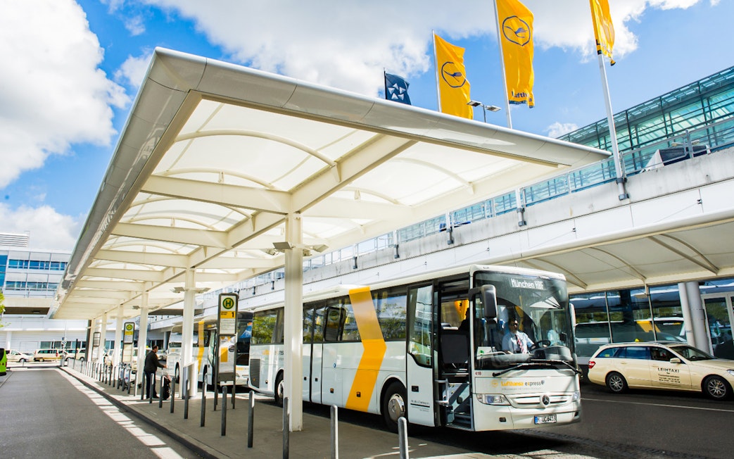 Lufthansa Express Bus at Munich Airport bus station with passengers boarding.