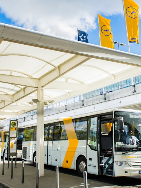 Lufthansa Express Bus at Munich Airport bus station with passengers boarding.