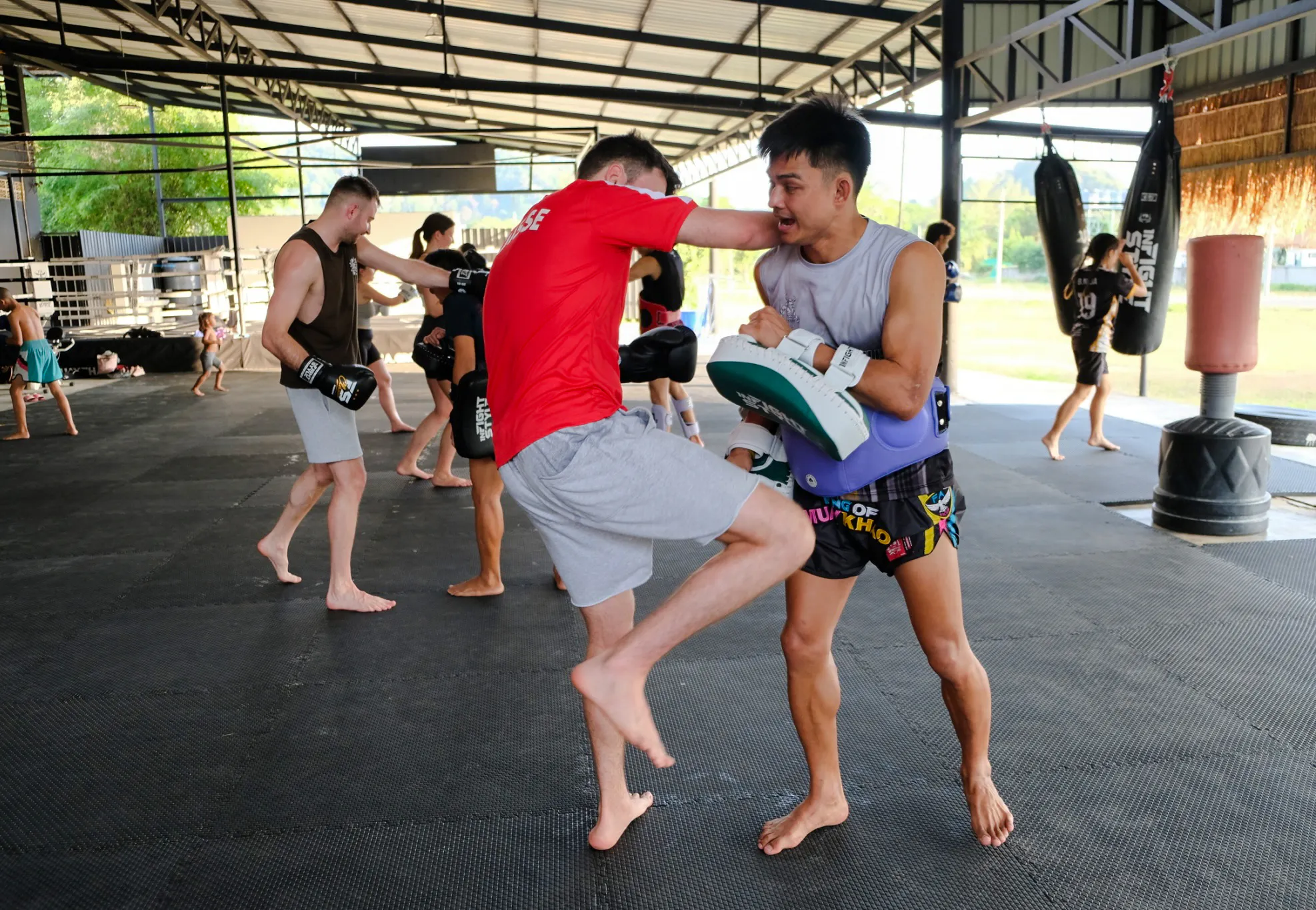 Muay Thai beginners practicing techniques in an open-air gym in Ao Nang, Krabi.