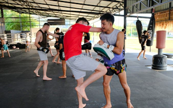 Muay Thai beginners practicing techniques in an open-air gym in Ao Nang, Krabi.