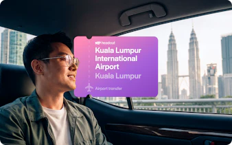 Man in car with view of Petronas Towers, Kuala Lumpur airport transfer.