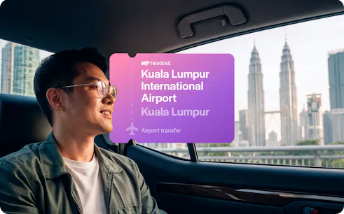Man in car with view of Petronas Towers, Kuala Lumpur airport transfer.