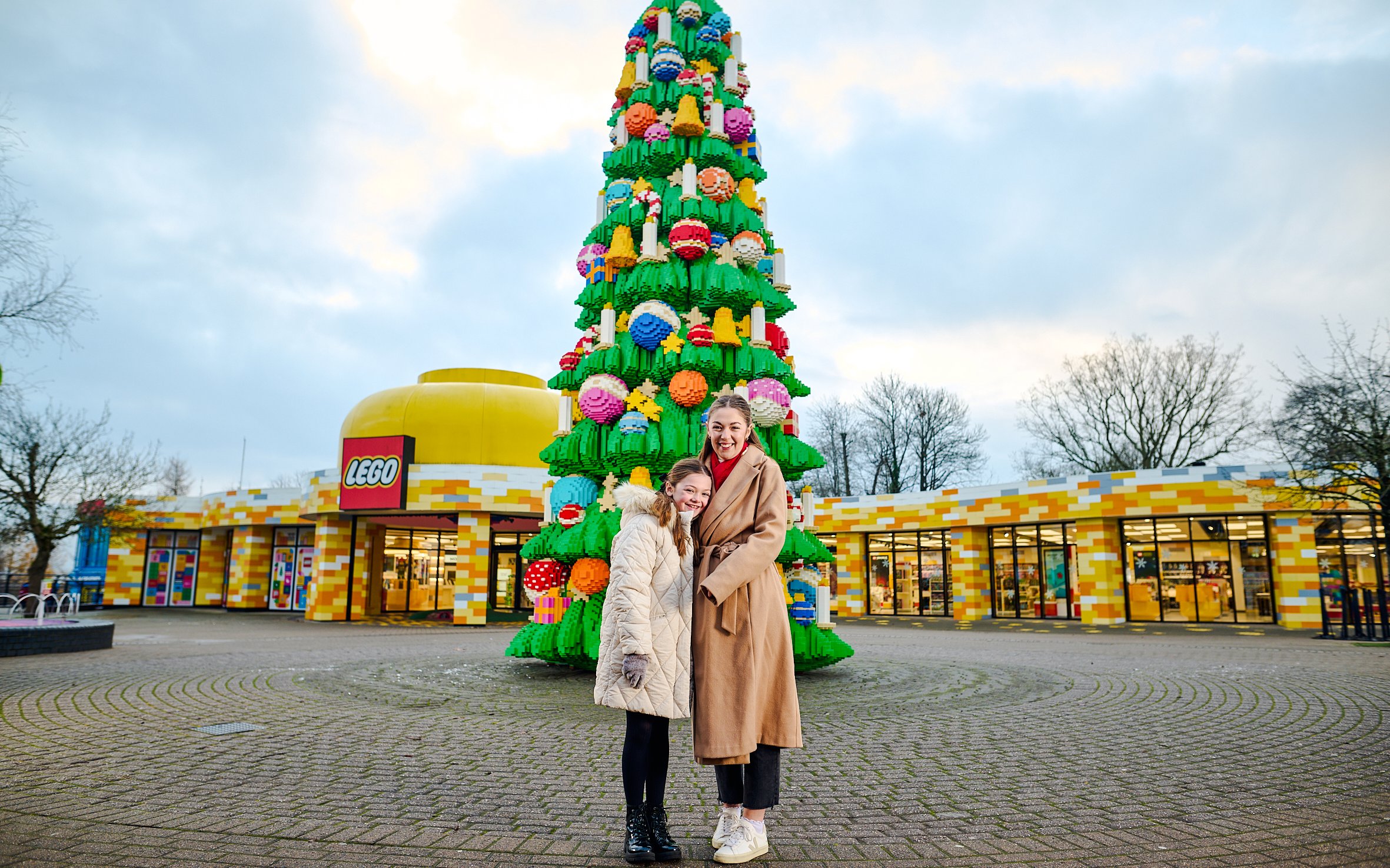 Guests at Legoland Windsor posing by a large LEGO Christmas tree.
