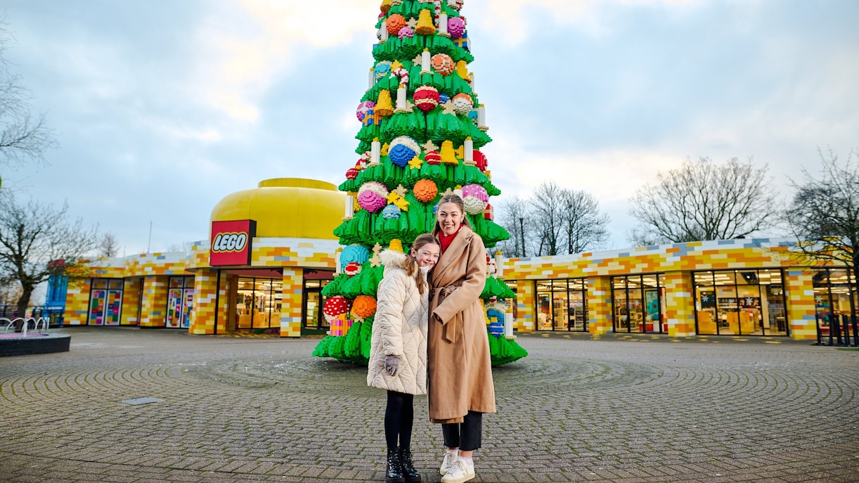 Guests at Legoland Windsor posing by a large LEGO Christmas tree.