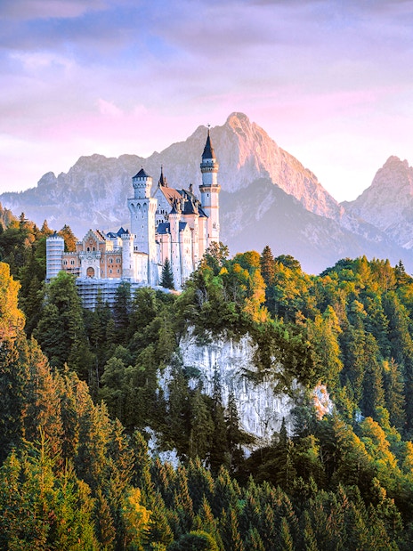 Neuschwanstein Castle surrounded by forested mountains in Bavaria, Germany.