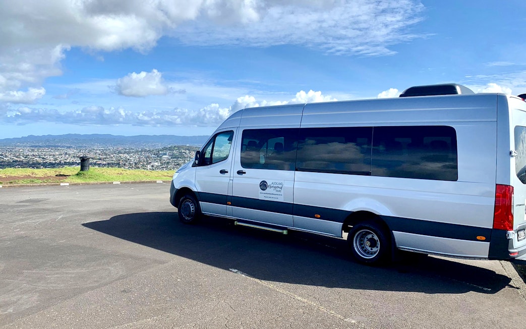 Transfer van parked with Auckland cityscape in the background, en route to Hobbiton Movie Set.