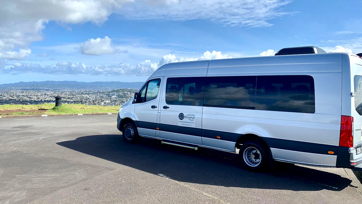 Transfer van parked with Auckland cityscape in the background, en route to Hobbiton Movie Set.
