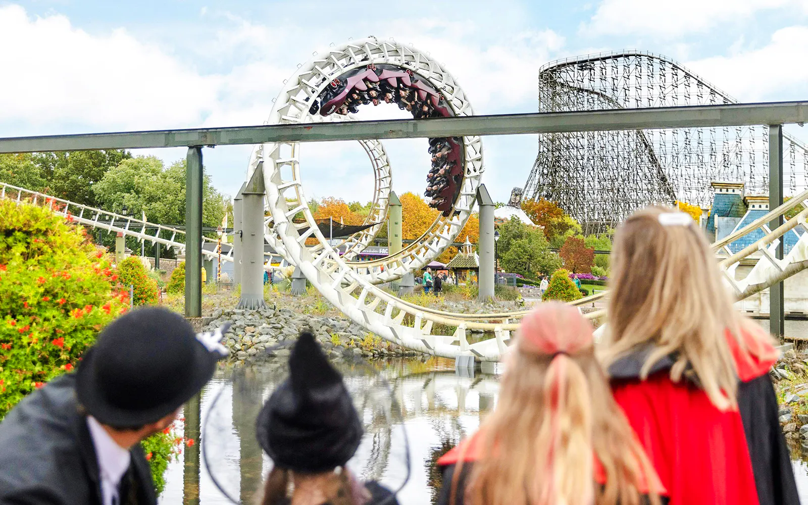 Roller coaster loop at Heide Park during Halloween event with visitors in costumes.