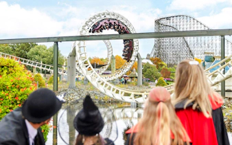 Roller coaster loop at Heide Park during Halloween event with visitors in costumes.