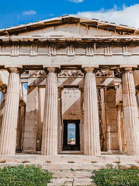 Temple of Hephaestus with Doric columns in Agora, Athens under blue sky.