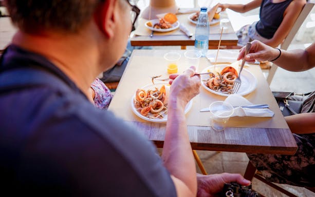 Dining on local cuisine during a guided art and food walking tour in Palermo.