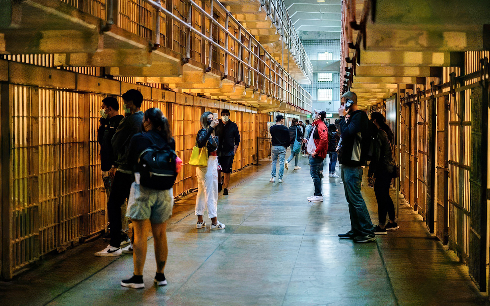 Visitors exploring Alcatraz Island cell block during night tour.
