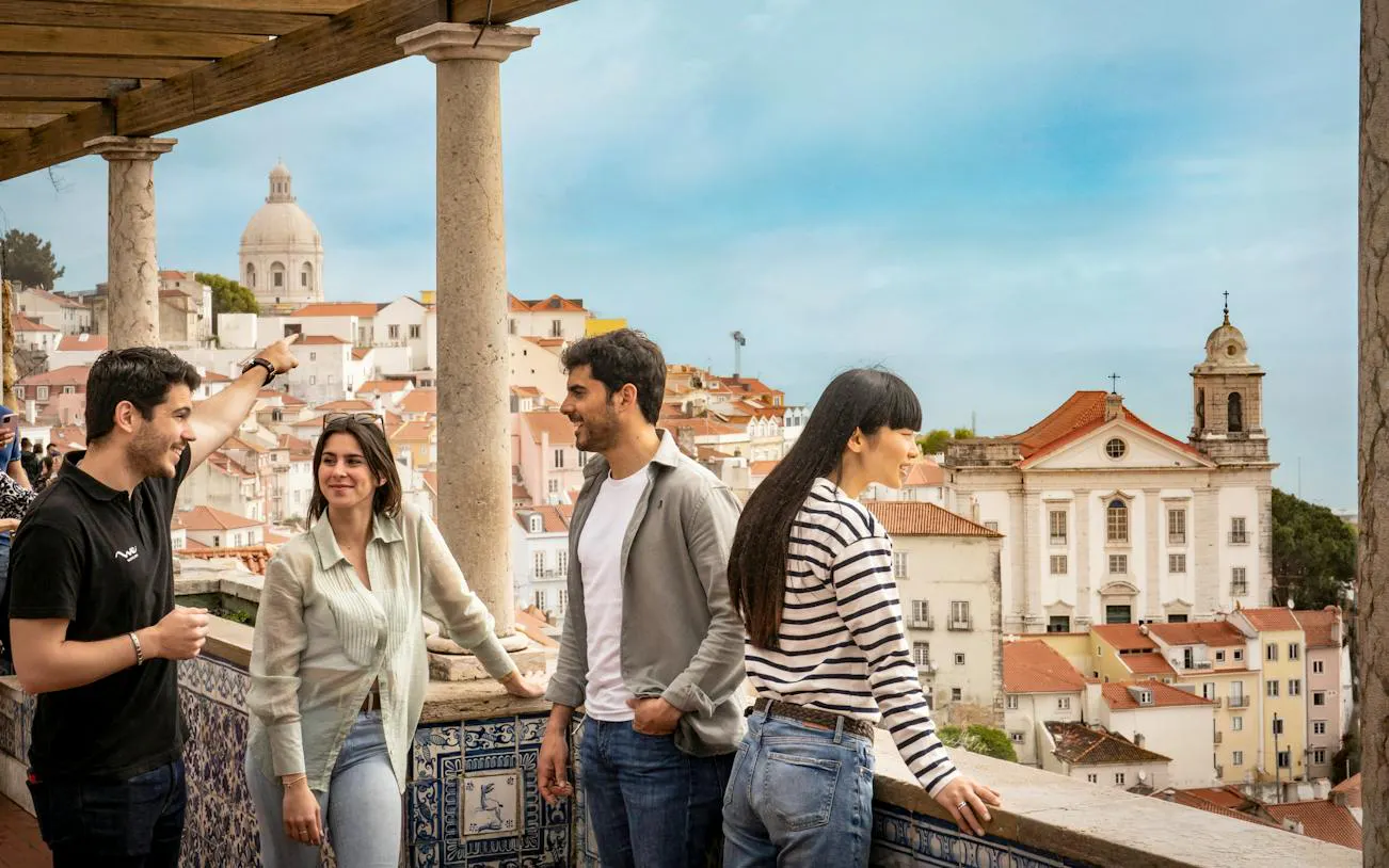 Group enjoying Lisbon view with historic buildings and dome in the background, part of a walking tour.