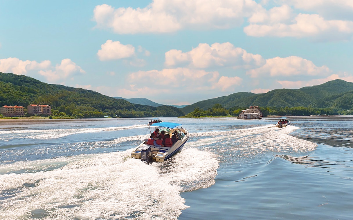 Boats cruising on the water with scenic views of Nami Island's lush hills.