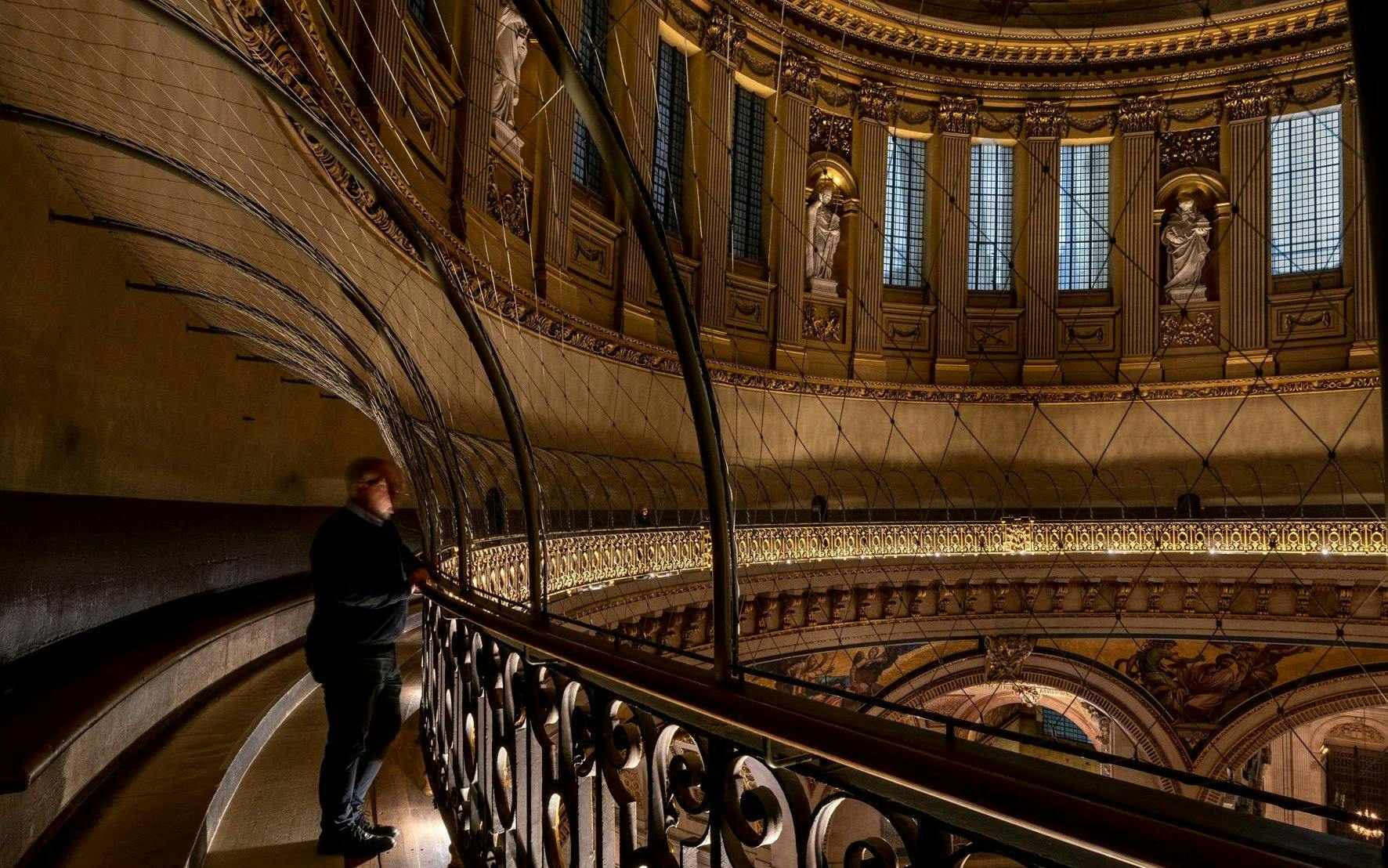 Interior view of St Paul's Cathedral dome with visitor on the Whispering Gallery.