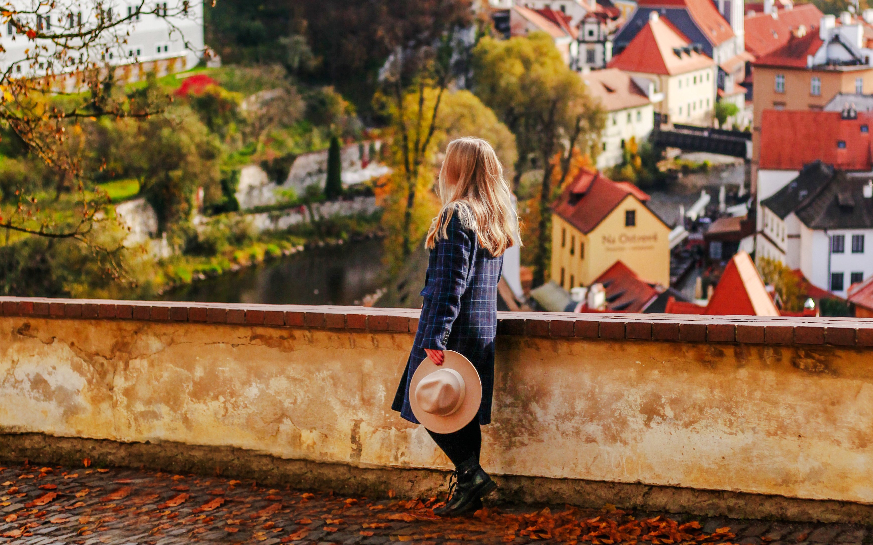 Girl tourist overlooking Cesky Krumlov rooftops and autumn landscape, Czech Republic.