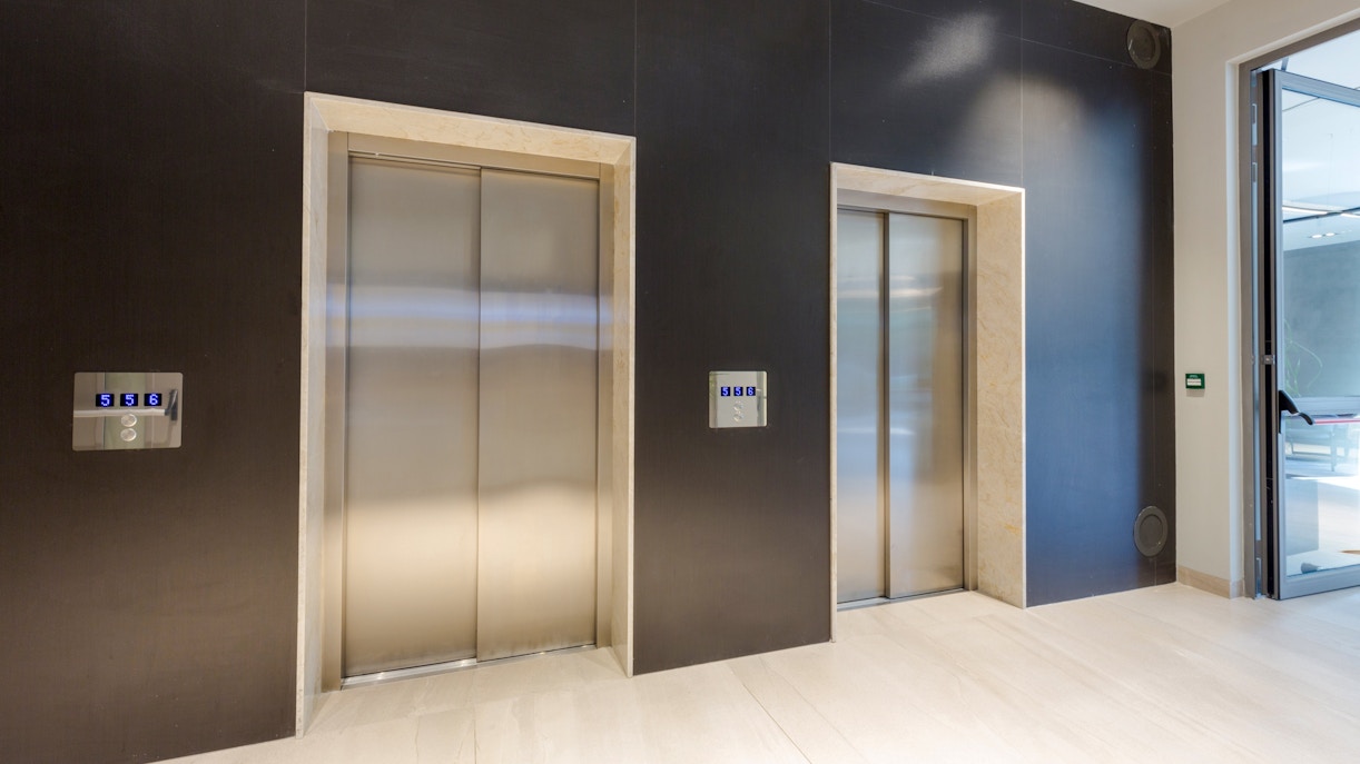 Lobby with two closed elevator doors and control panels.